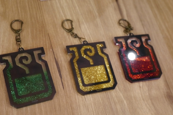 글리터 키홀더(총 3종, 각 1320엔)은 '회복약', '귀인약', '강주약' 아이콘 모양의 열쇠고리로, 기울이면 내용물이 움직인다.